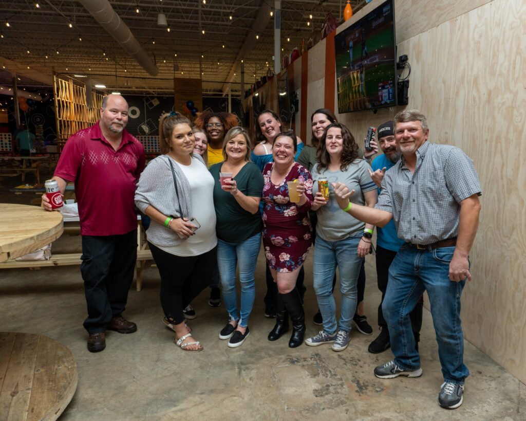 Group of friends smiling with drinks at Rec Hall in St. Charles, Missouri, ready for game night after learning the 9 ball rules