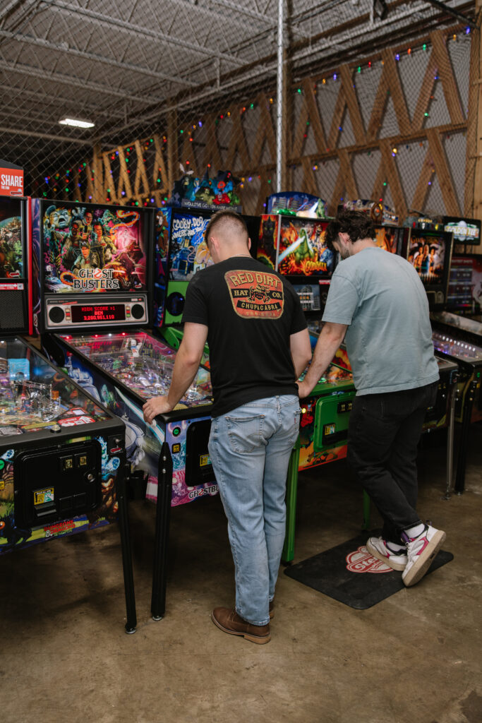 Friends playing pinball at Rec Hall in St. Charles, Missouri, one of the best bar games for groups